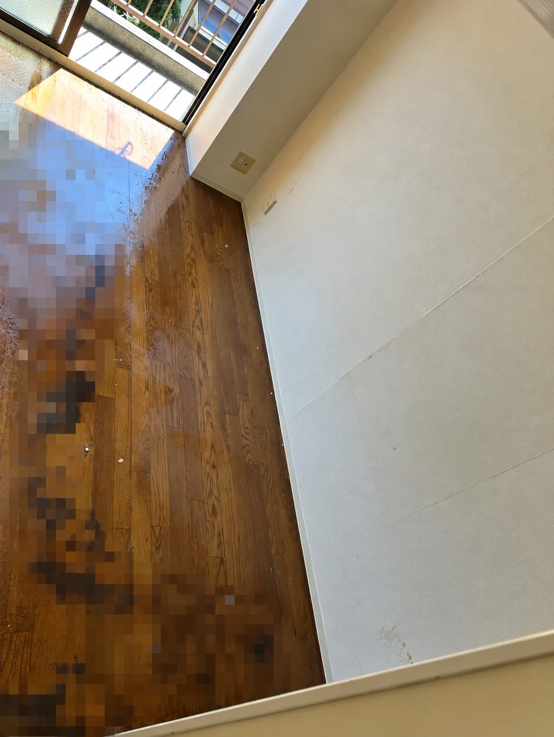 名古屋市西区の特殊清掃、残置物撤去後に床の汚染範囲を確認している様子（一部モザイク処理）
